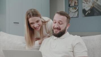 Couple, laptop and online banking, hug and ecommerce shopping, social media or funny internet post in home. Man, woman and pc technology, happy smile and internet with happiness together in house. video