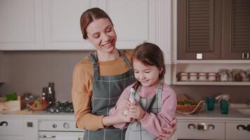 Mom and daughter are preparing a cake. My daughter is a hooligan and eats cream. while mom is laughing. Happy family. Real emotions. video