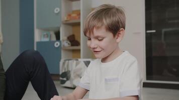 il nipote giochi con il suo nonno nel giocattoli. costruisce un' costruttore. il ragazzo è giocando a casa. carino emozioni nel il telaio. il storia di uno famiglia. video