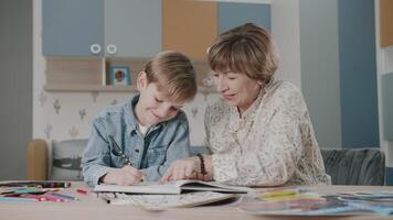 grand-mère et petit fils sont Faire devoirs. portrait de une content famille. apprentissage à maison. enseignement. grand-mère et petit fils rire. mignonne émotions dans le Cadre. le récit de un famille. video