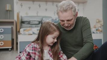 The granddaughter plays with her grandfather in toys in the nursery. They laugh and joke at each other. Portrait of a sweet and happy family. Vivid emotions . The story of one family video