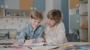 Grandma and grandson are doing homework. Portrait of a happy family. Learning at home. Teaching. Grandmother and grandson laugh. Cute emotions in the frame. The story of one family. video