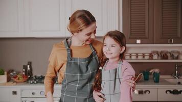 While making a cake, Mom smears her daughter's nose with cream, after which they laugh. A young woman and a child have a good time in the kitchen in their house. Happy family. video