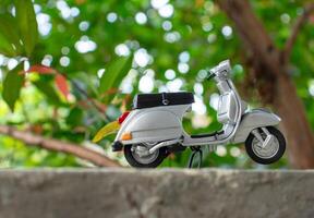 Miniature classic scooter on the cement floor with nature background. After some edits. photo