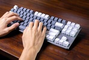 A modern mechanical keyboard and hands on a wooden table. After some edits. photo