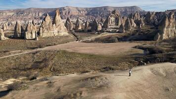 Aerial drone view of a person admiring the natural beauty of the Rose Red Valley in Cappadocia, Turkey. Famous destination for hikers to explore the Rock Sites of Cappadocia. video