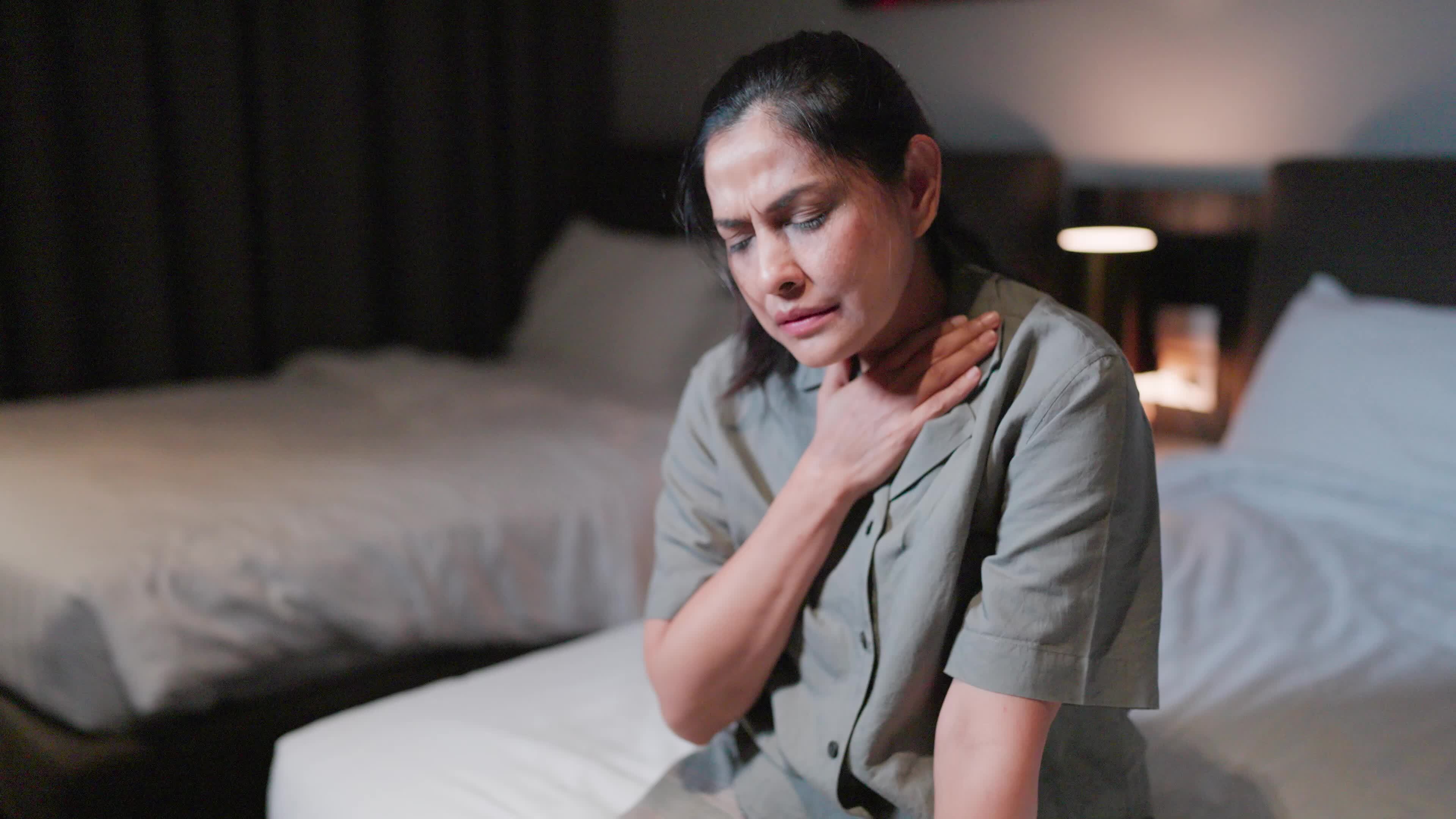 Woman has heart pain sitting on the bed in the bedroom after waking up
