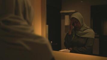 A woman wearing a hijab stands worried about her married life after getting dressed in the shower. video