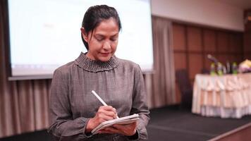 Woman using tablet computer and digital pen in front of stage of show room at work video