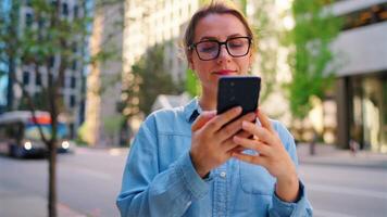 caucasiano mulher é caminhando por aí a cidade e usando Smartphone video