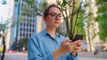 Caucasian woman is walking around the city and using smartphone video