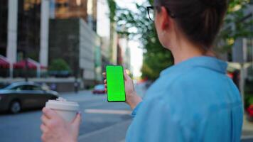 vrouw is staand Aan de straat en gebruik makend van smartphone met groen scherm video