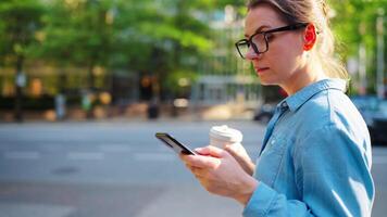 caucasiano mulher dentro óculos caminhando por aí a cidade e usando Smartphone video