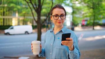 Caucasian woman in glasses walking around the city and using smartphone video