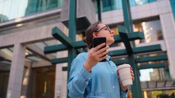 Caucasian woman in glasses stands on the street and using smartphone video