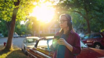 Woman is standing outdoors near the red vintage car and using smartphone video