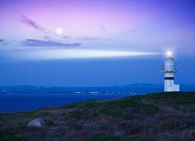 Lighthouse beaming light ray over stormy clouds photo