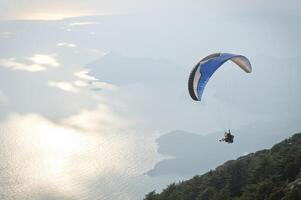 Parachute skydiver flying in clouds at top of mountains photo