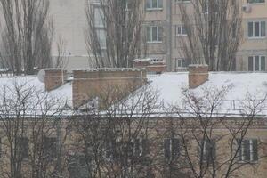 techos y chimeneas cubierto con nieve en invierno foto