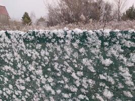 Snow fell on the fence in the village photo