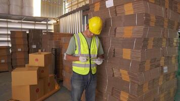 Portrait of asian engineer man order details checking goods and cardboard box with goods background in warehouse.logistic and business export.Product Distribution Logistics Center. video