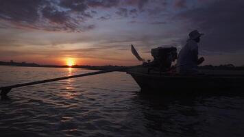 silueta de un pescadores en barco con fuera de borda motor barco Listo a pescar durante hermosa amanecer. video