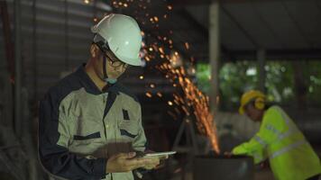 profesional pesado industria ingeniero y trabajador vistiendo la seguridad uniforme y difícil sombrero usos tableta comprobación acero. éxito industria concepto. video