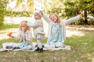 3 sisters at a picnic playing with soap bubbles. Summer holidays 3 blonde girls. photo