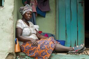 ai generado un africano mujer sentado triste fuera de su casa. el color de África foto