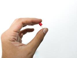 dedos de un mano participación un cápsula píldora aislado en un blanco antecedentes foto