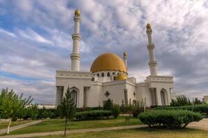 Gurbanguly Mosque in Mary, Turkmenistan, white marble, gold roof and a clouded sky. photo