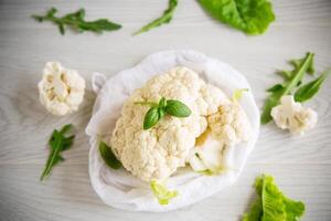 inflorescences of small cauliflower on a light wooden table photo