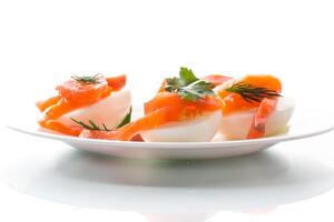 halves of boiled eggs with pieces of salted salmon on white background photo