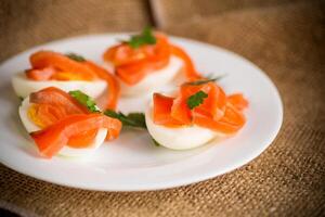 halves of boiled eggs with pieces of salted salmon photo