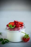 Sweet homemade yogurt with fresh ripe strawberries in a glass jar photo