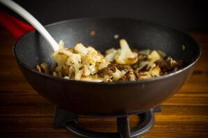 fried cauliflower with wild porcini mushrooms and onions in a pan photo