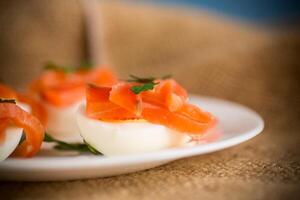 halves of boiled eggs with pieces of salted salmon photo