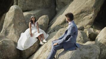 Bräutigam mit Braut sitzen auf ein Steigung von das Berg. Hochzeit Paar. glücklich video