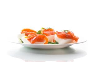 mitades de hervido huevos con piezas de salado salmón en blanco antecedentes foto