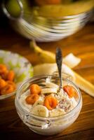 cooked boiled sweet oatmeal with with dried apricots and bananas in a bowl photo