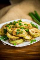 fried zucchini in circles with fresh herbs in a plate photo