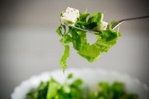 Fresco verde lechuga ensalada con queso Mozzarella y hierbas en un tenedor foto