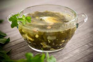 Spring soup from fresh sorrel with boiled eggs in a plate photo