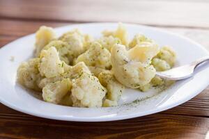 Cooked cauliflower, steamed, in a plate with spices . photo