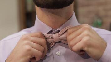 Groom adjusts bow tie in barbershop background. Preparing to go to the bride video