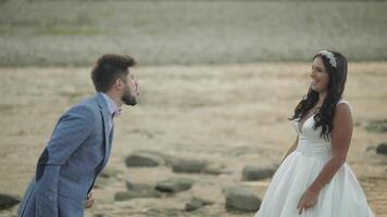 Wedding couple standing near mountain river. Groom and bride making faces video