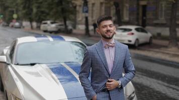 novio cerca deporte coche en calle. rosado camisa, arco atar, azul chaqueta. empresario video