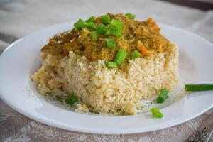 cooked bulgur with meat sauce and vegetables in a plate photo