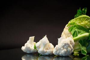 slices of raw small raw cauliflower on black background photo