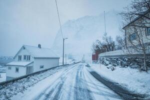 pescar pueblo con nieve montaña en el la carretera en nieve tormenta en invierno a lofoten islas foto